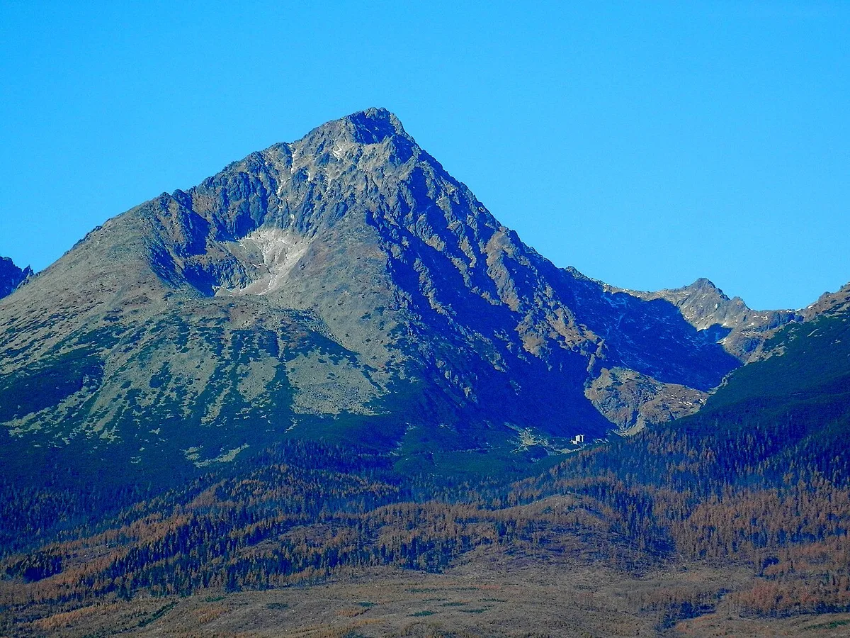 Herfstelijke berghellingen in de Hoge Tatra met geel verkleurd bos en daarboven een kale rotstop.